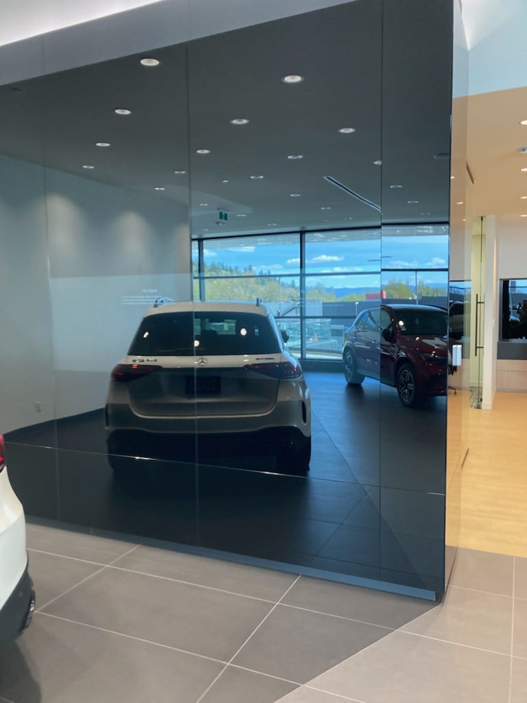 White Mercedes SUV in showroom reflecting in black glass wall